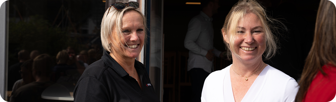 Two employees smiling and chatting at a company event.